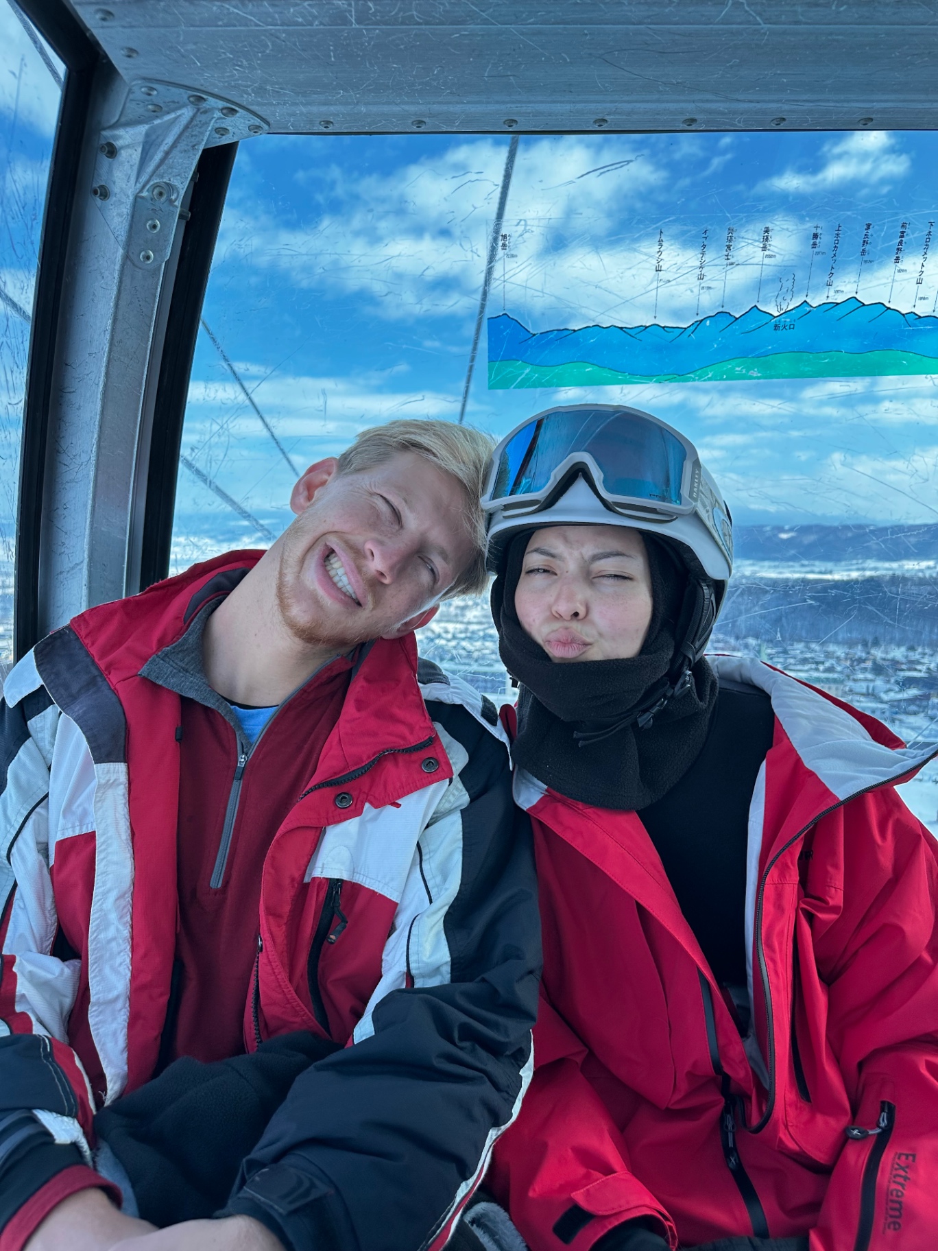 Jono & Monika together in a ski gondola, both in red